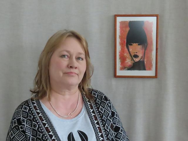 Taiteilija Helena Junttila, valokuva naisesta maalatun muotokuvan vieressä