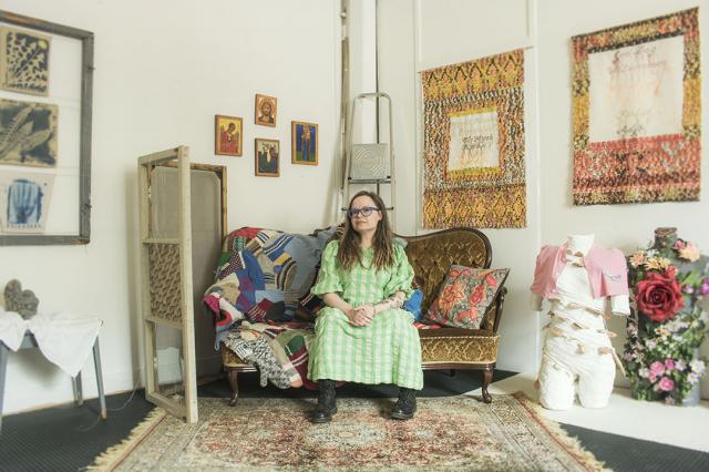 Artist Christa Friberg sitting on a sofa in her artist studio