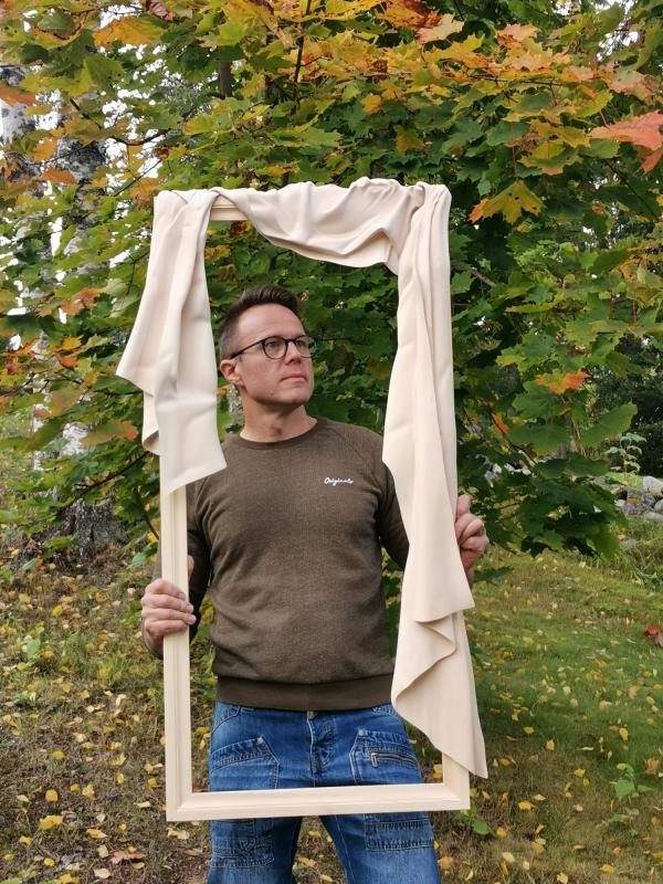 Tero Hulkkonen lehmuksesta veistetyn kehyksen sisällä.